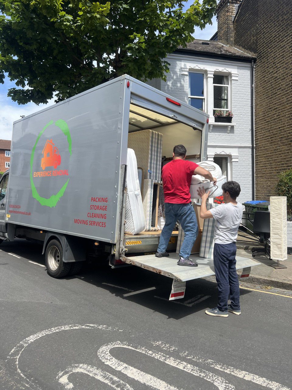 Two movers carrying items into the back of a moving truck